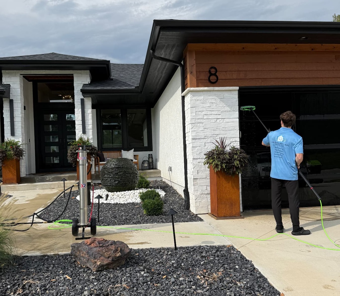 Happy Home Services technician using a XERO Pure Package water-fed pole system to clean windows on a home